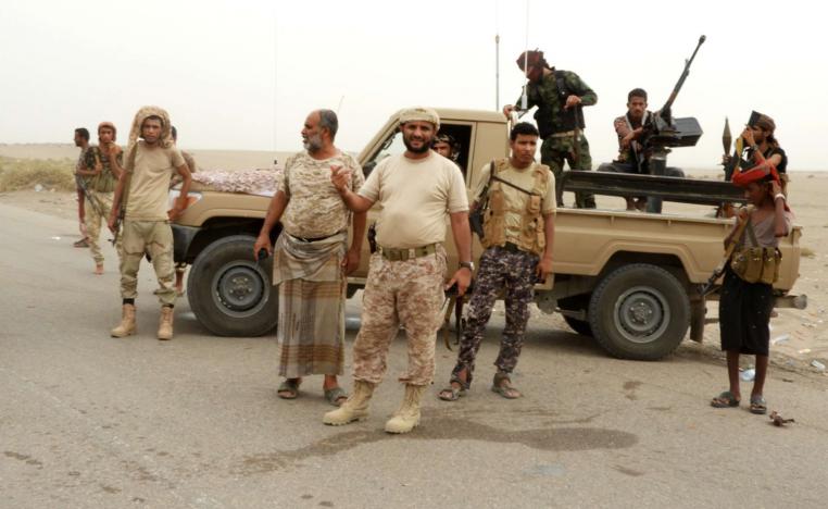 Yemeni pro-government forces stand next to a pickup truck carrying anti-aircraft guns outside Hodeidah