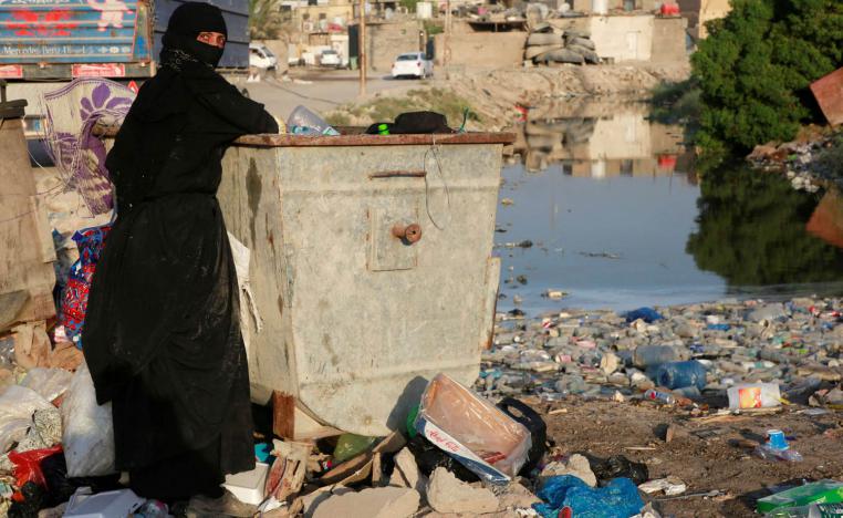 عراقية تبحث في الزبالة عن مواد يمكن بيعها في البصرة