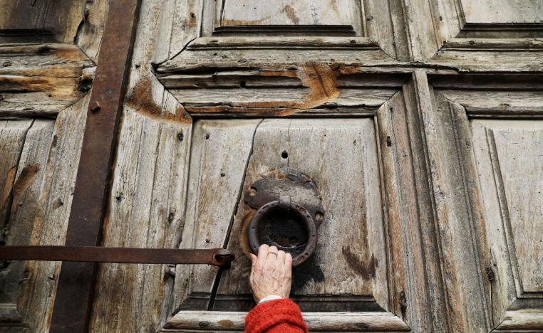 A worshipper touches the closed doors of the Church of the Holy Sepulchre.