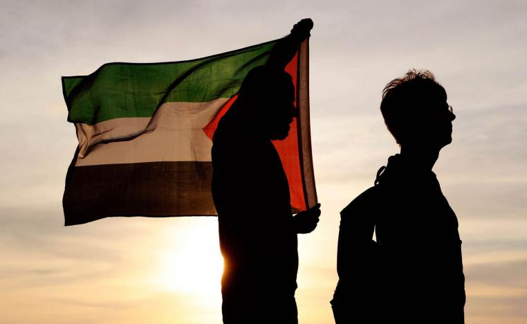 فلسطينيان يرفعان علم بلادهما قرب الحدود بين غزة وإسرائيل