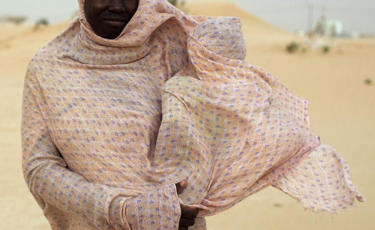 A woman shields her child from the wind while walking on sand dunes near Nouakchott, Mauritania.