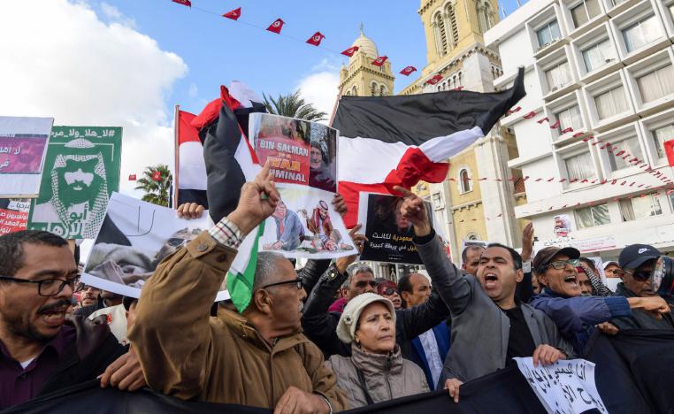 Tunisians shout slogans and hold up signs as they protest against the expected visit of the Saudi Crown Prince.