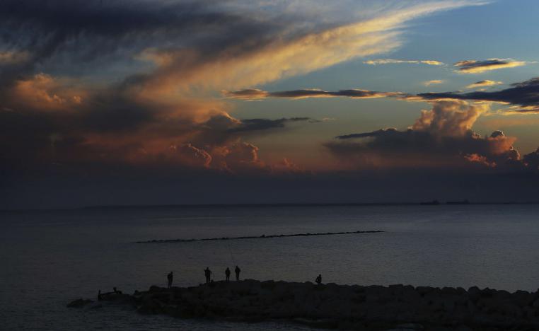 Men fishing with their fishing rods at the sea during a sunset in the southern port city of Limassol, Cyprus, Friday, Feb. 23, 2018.