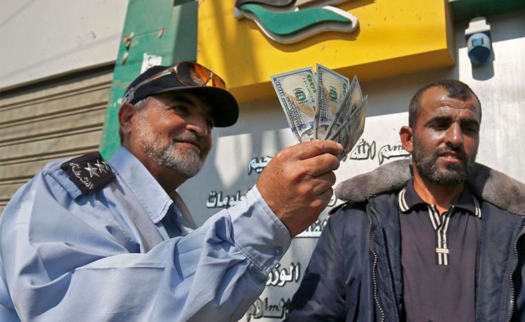 A Palestinian man shows his money after receiving his salary in Rafah in the southern Gaza Strip