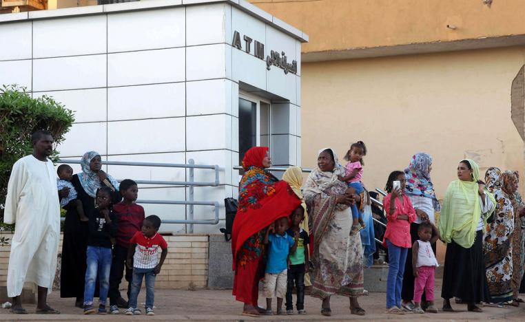Residents stand outside an automated teller machine (ATM) in Khartoum