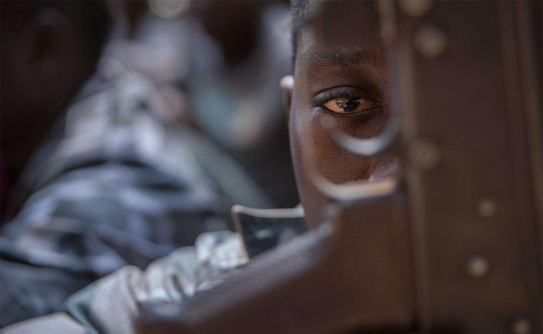 A released child soldier last February looks through a rifle trigger guard during a release ceremony for child soldiers in Yambio, South Sudan