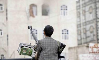 A Houthi fighter holds a weapon as he looks at smoke rising from a building in Sana’a