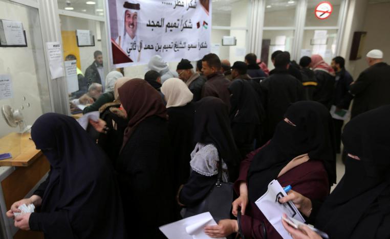 Palestinian Hamas-hired civil servants wait to receive their salaries paid by Qatar as a banner showing a picture of Qatar's Sheikh Tamim bin Hamad Al Thani is seen, in Khan Younis in the southern Gaza Strip December 7, 2018.