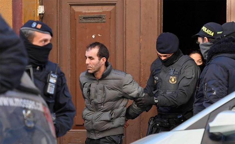 A man is escorted by Catalan regional police officers 'Mossos D'Esquadra" during a counter-terrorism operation