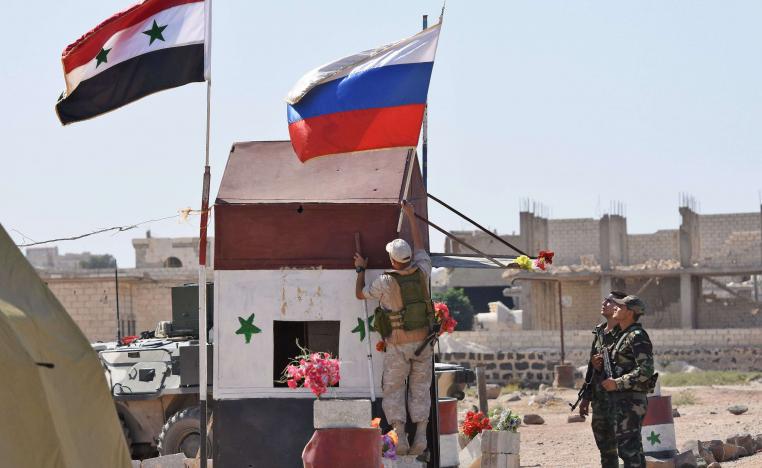 Russian soldiers place the national flag at the Abu Duhur crossing on the eastern edge of Idlib province on September 25, 2018, as Syrian families cross from rebel-held areas to regime-held areas.