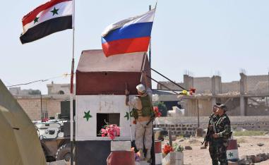 Russian soldiers place the national flag at the Abu Duhur crossing on the eastern edge of Idlib province on September 25, 2018, as Syrian families cross from rebel-held areas to regime-held areas.