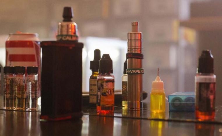 An assortment of e-liquids sit next to two portable vaporisers.