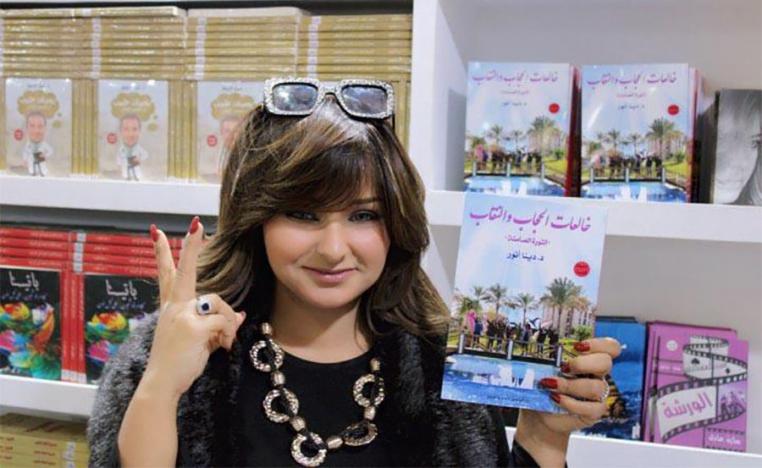 Dena Anwer holding her book "Those Taking Off the Hijab: The Silent Revolution"