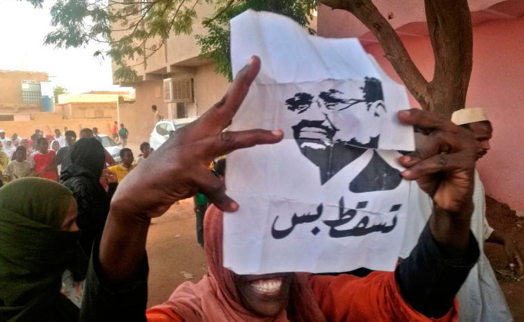 A Sudanese protester carries a portrait of President Omar al-Bashir with Arabic writing that reads "down and that is all" during an anti-government demonstration east of the capital Khartoum on February 9, 2019.
