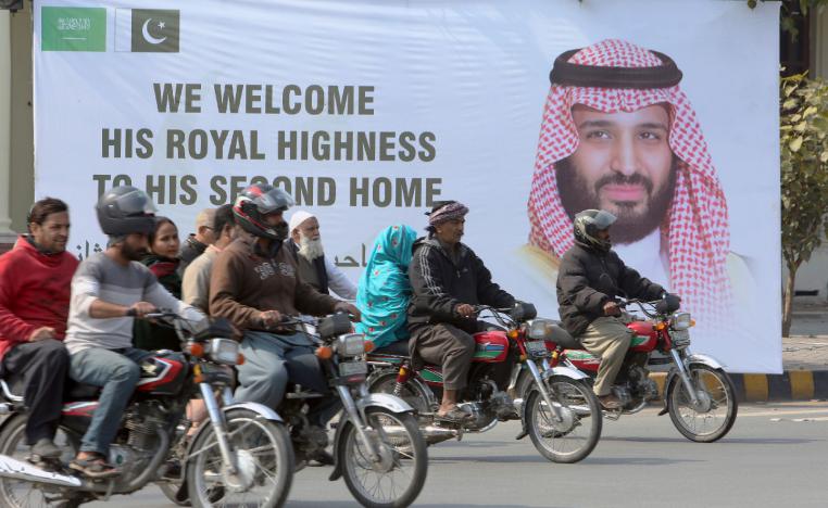 Pakistani motorcyclists pass by a banner welcoming Saudi Arabia's Crown Prince Mohammed bin Salman displayed on the occasion of his visit, in Lahore, Pakistan, Saturday, Feb. 16, 2019.