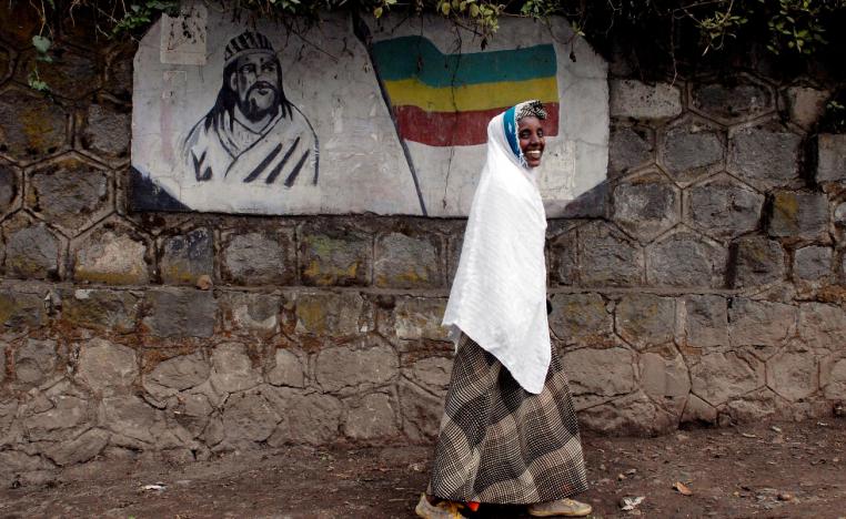 A traditionally-dressed Ethiopian woman walks past a mural depicting Ethiopia's Emperor Tewodros II in Addis Ababa, Ethiopia, June 1, 2007.