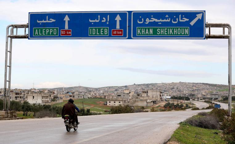 Two Syrian men drive past road signs in Khan Sheikhun on February 28, 2019.