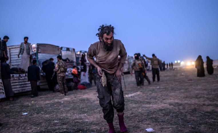 A man suspected of belonging to the Islamic State (IS) group walks past members of the Kurdish-led Syrian Democratic Forces (SDF) just after leaving IS' last holdout of Baghouz, in the eastern Syrian province of Deir Ezzor on March 4, 2019.