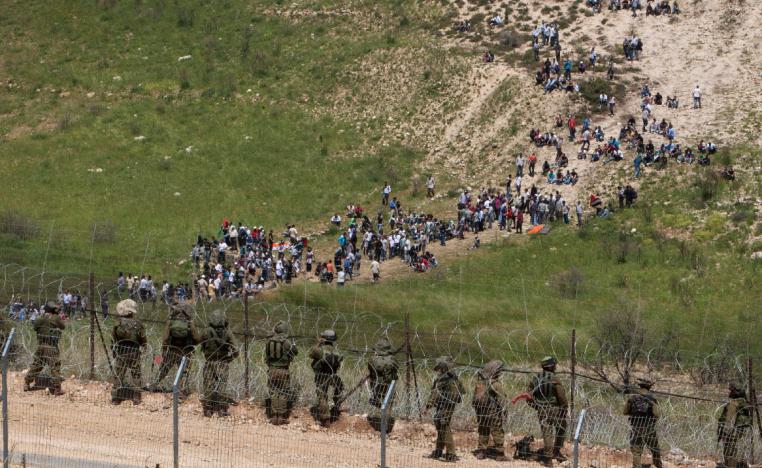 Israeli troops take positions, front, as pro-Palestinian protesters approach the border between Israel and Syria near the village of Majdal Shams in the Golan Heights.