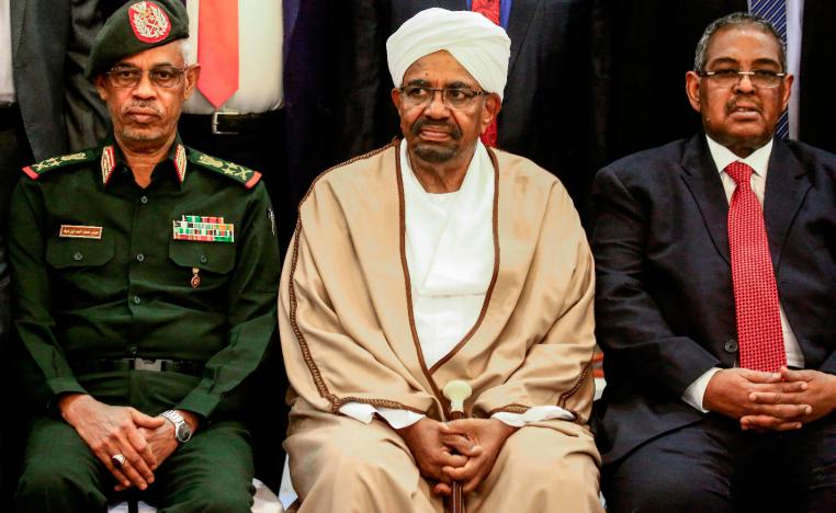 Sudan's President Omar al-Bashir (C) is seated alongside his first vice president Lieutenant General Awad Mohamed Ahmed ibn Auf (L) and Prime Minister Mohamed Tahir Eila (R) as they pose for a group photo with members of the new 20-member cabinet taking oath at the presidential palace in the capital on March 14, 2019.