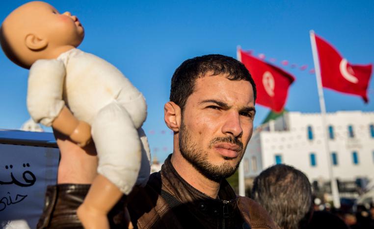 A Tunisian protester holds a baby doll in Tunis to denounce the deaths of babies in Tunisian hospital, Tuesday, March 12, 2019.