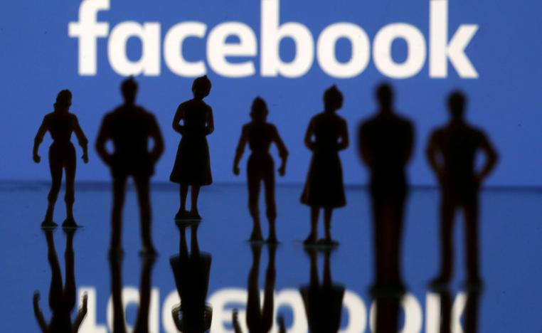 دمى بشرية صغيرة تقف أمام شعار فيسبوك