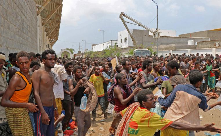 African migrants receive food and water inside a football stadium in the Red Sea port city of Aden