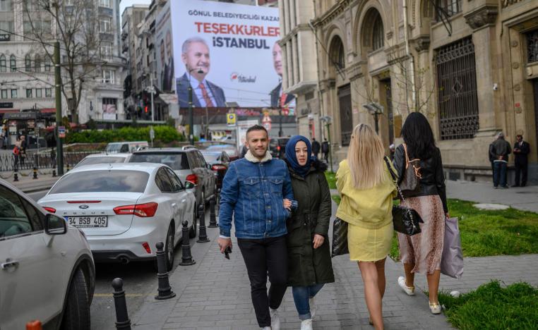 People go about their daily life next to a billboard reading "Thank You Istanbul" and portraying AKP ruling party mayor candidate Binali Yildirim and President Recep Tayyip Erdogan, in Istanbul, on April 2, 2019.