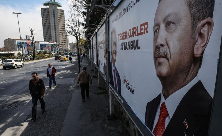 People walk past posters showing Turkey's President Recep Tayyip Erdogan and Binali Yildirim, the mayoral candidate for Istanbul of the ruling Justice and Development Party (AKP) a day after the local elections in Istanbul, Monday, April 1, 2019.