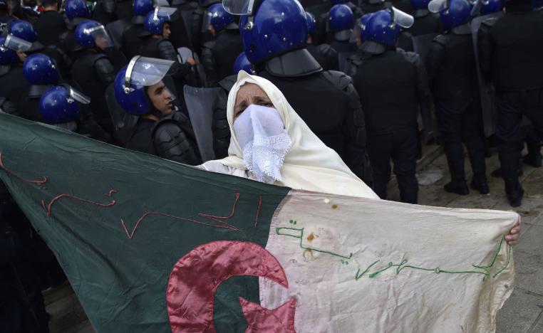 An Algerian woman holds a flag near security forces cordoning-off a protest area during an anti-system demonstration in the capital Algiers on April 10, 2019.