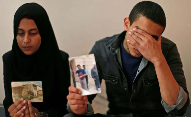 The daughter (L) and son of Zaki Mubarak hold his picture
