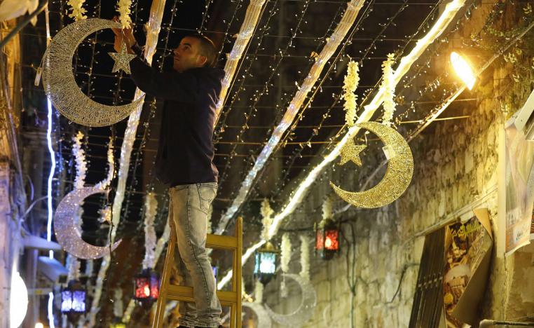 شاب فلسطيني يعلق زينة رمضان بالقرب من مجمع المسجد الأقصى في مدينة القدس القديمة