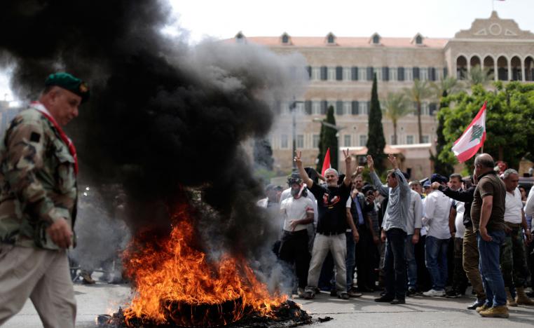 Lebanese retired soldiers burn tires as they protest in front of the government building during a cabinet meeting to discuss an austerity budget