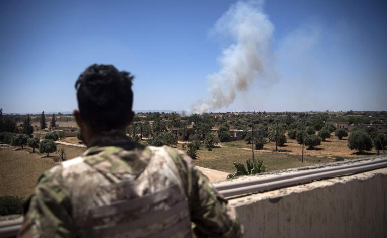 A fighter loyal to the GNA watches as smoke rises in the distance