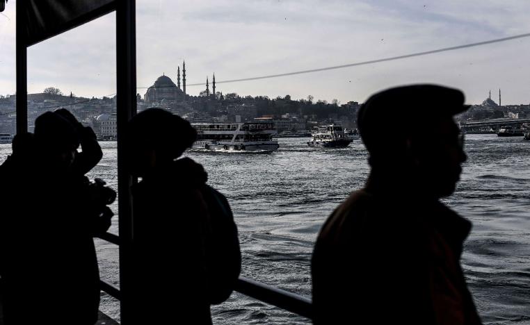 People stand on Galata bridge in Istanbul as Suleymaniye mosque is seen in the background