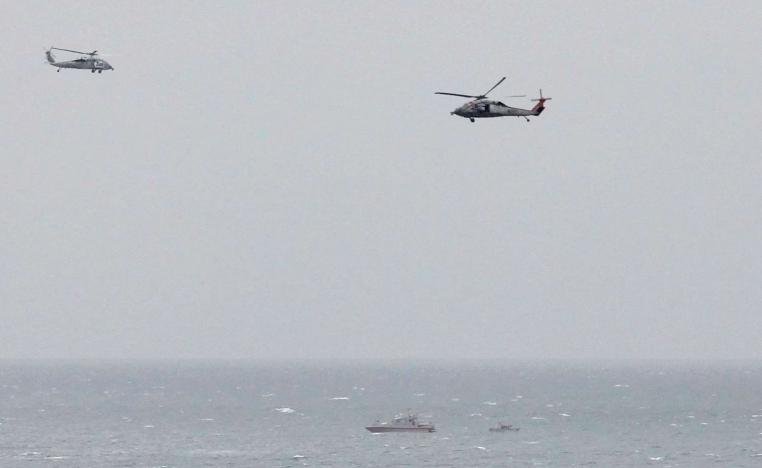 Iranian Revolutionary Guard boat is seen near the U.S. aircraft carrier USS George H. W. Bush in the Strait of Hormuz as U.S. Navy helicopters hover nearby