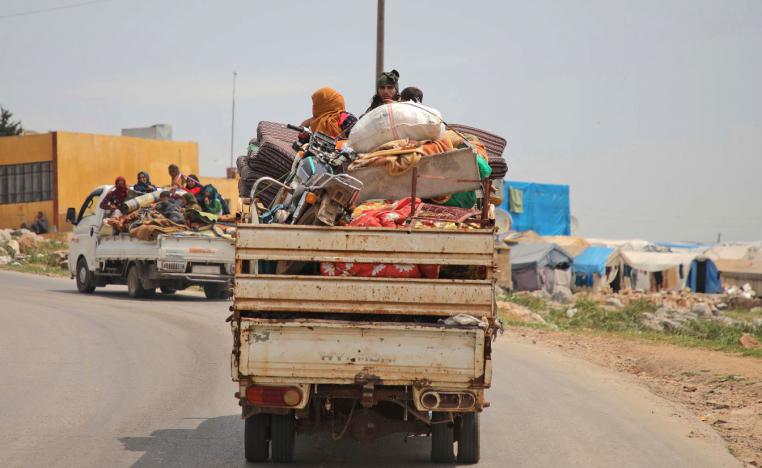 Syrian families, riding in the back of trucks loaded with their belongings, flee from reported regime shelling on Hama and Idlib provinces
