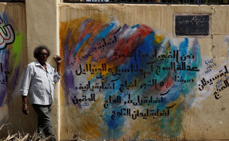Rashid Drar, a 44-year old artist, poses next to graffiti in Khartoum