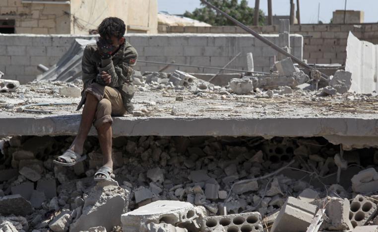 A man sits amidst the rubble of a building in Idlib, destroyed during airstrikes by the Syrian regime