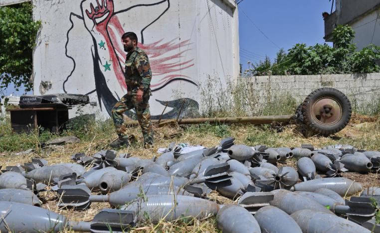 A Syrian government soldier walks past mortar shells in the village of Qalaat al-Madiq