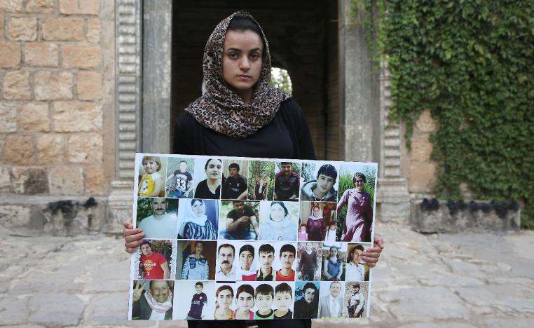 Yazidi woman Ashwaq Haji, allegedly used by the Islamic State group (IS) as a sex slave, holds portraits of jihadists' victims from her village of Kocho near Sinjar