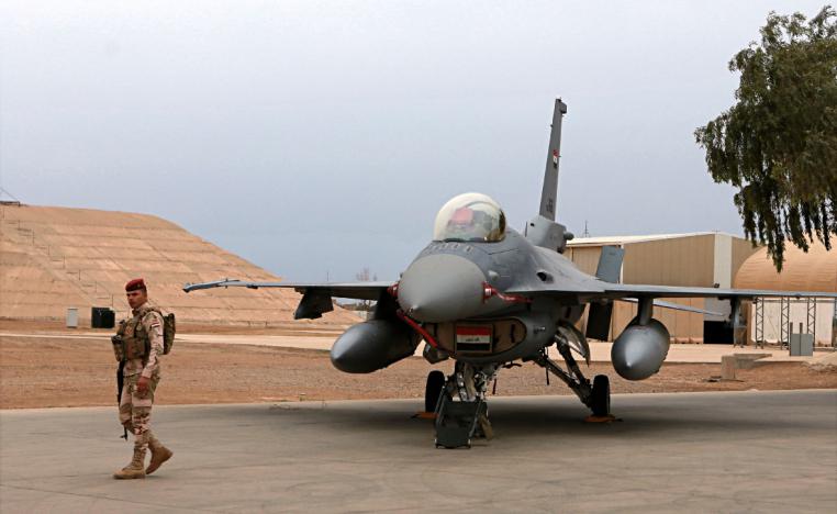 An Iraqi army soldier stand guard near a US-made fighter jet at the Balad Air Base