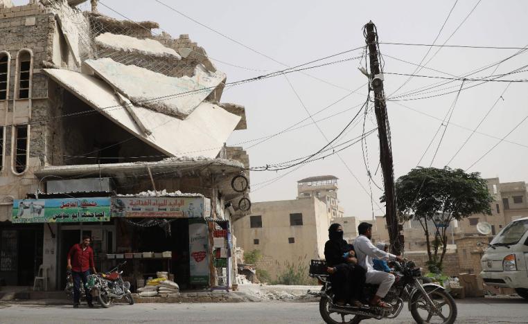 A man drives his motorcycle past a damaged building in the town of Binnish