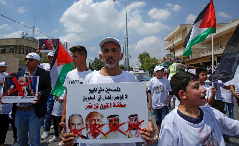 A man holds a protest sign with a caption in Arabic reading "Palestine is not for sale"
