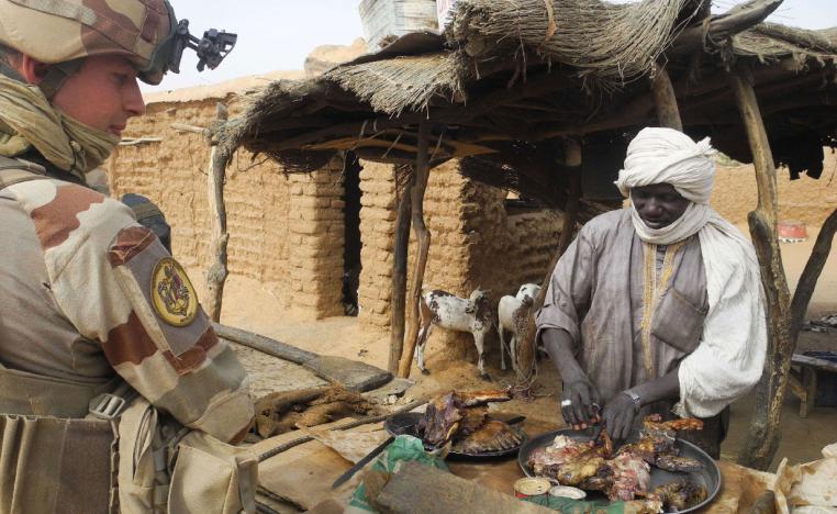 A French soldier speaks with a shopkeeper selling meat at his stall, in Gossi, central Mali