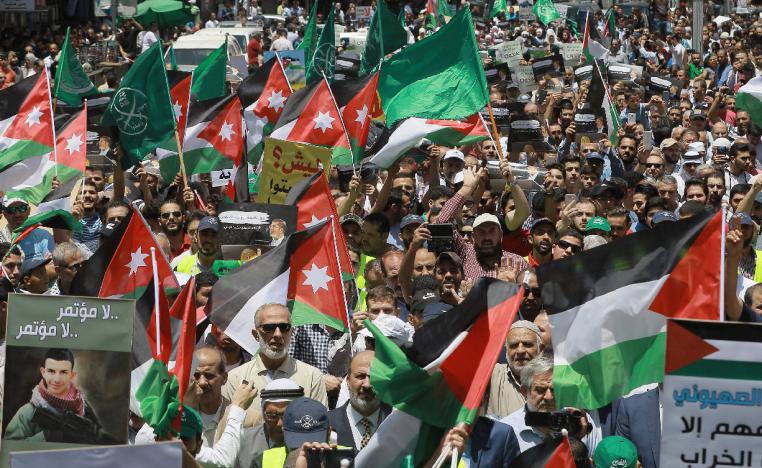 Flags of Jordan and the Muslim Brotherhood are waved with other protest signs denouncing the US-led Middle East economic conference in Bahrain