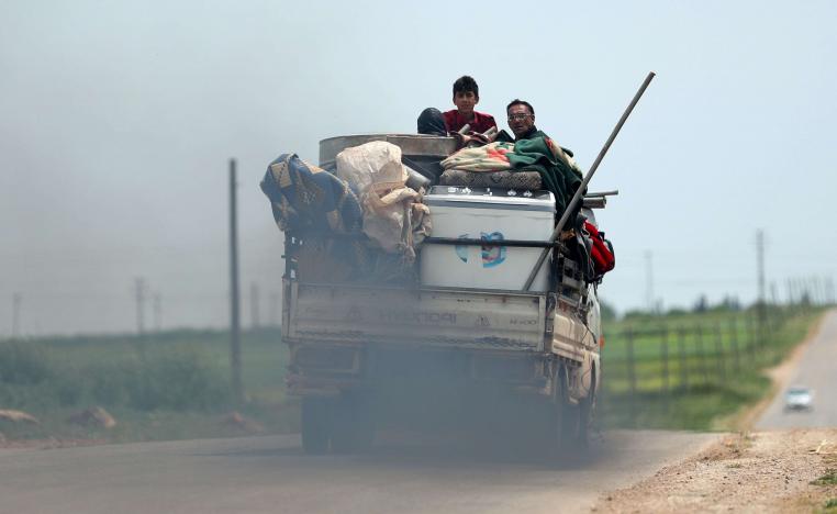 A displaced Syrian family rides in the back of a truck loaded with furniture and clothes