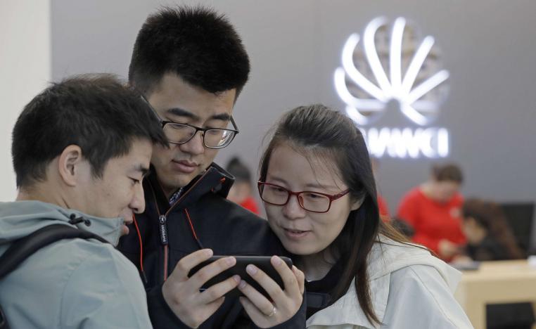 زبائن صينيون يطالعون هاتفا من هواوي في أحد متاجر الشركة في مقاطعة غوانغدونغ