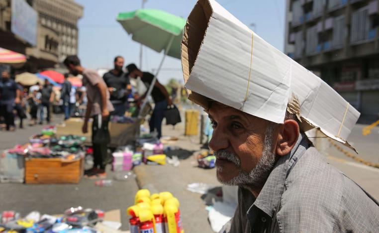 بائع متجول عراقي يحمي رأسه من الشمس باستخدام الكرتون  خلال موجة الحر في بغداد