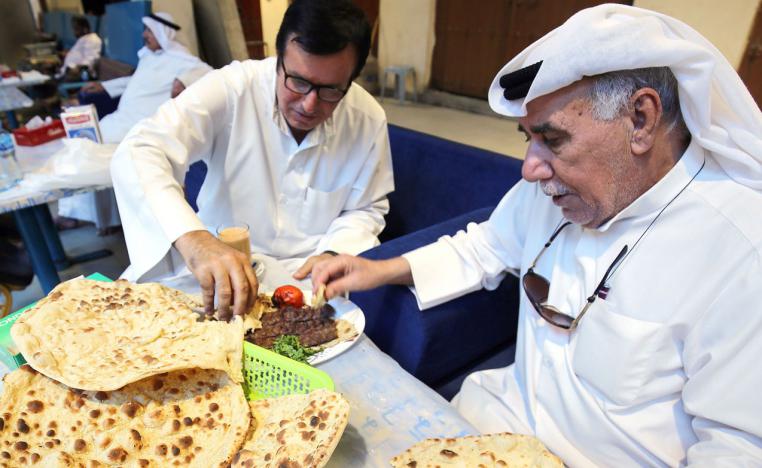 Hassan Abdullah Zachriaa, a Kuwaiti of Iranian origin and owner of the Al-Walimah restaurant, shares Iranian bread - known as taftoon - during a meal with a friend in Kuwait City